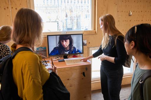 Personer står och tittar på en film på en skärm